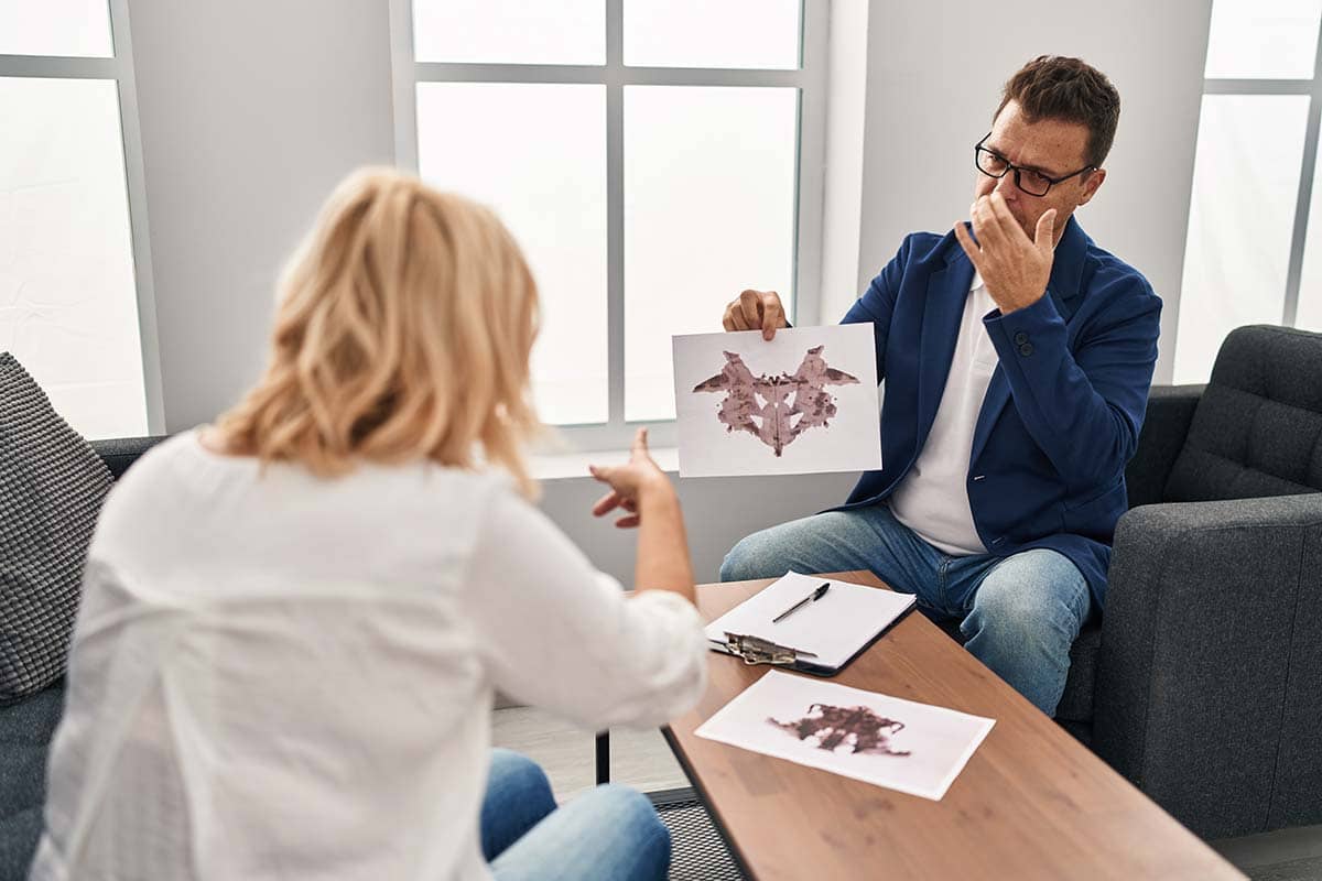 Middle age man and woman psychologist and patient doing rorschach test at psychology center