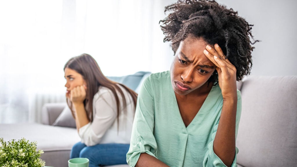 two women facing away from each other, head in their hands, frustrated and confused